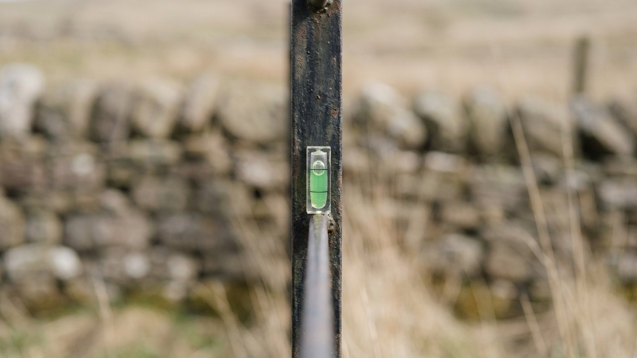 Vérification de la verticalité d'un piquet de clôture en fer au niveau à bulle